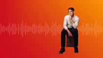 Ein Mann sitzt auf einem Holzhocker vor einem rot‑orangefarbenen Hintergrund mit stilisierten Soundwellen, die sich horizontal über das Bild ziehen. Ein Mann sitzt auf einem Holzhocker vor einem rot‑orangefarbenen Hintergrund mit stilisierten Soundwellen, die sich horizontal über das Bild ziehen.