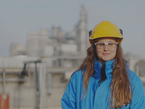 Eine Ingenieurin mit Schutzhelm und Schutzbrille steht vor einer Industrieanlage. Eine Ingenieurin mit Schutzhelm und Schutzbrille steht vor einer Industrieanlage.